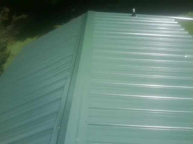 New green metal panels meeting at the ridge of a roof — Flat Roof Repair work by our crew in Cresskill
