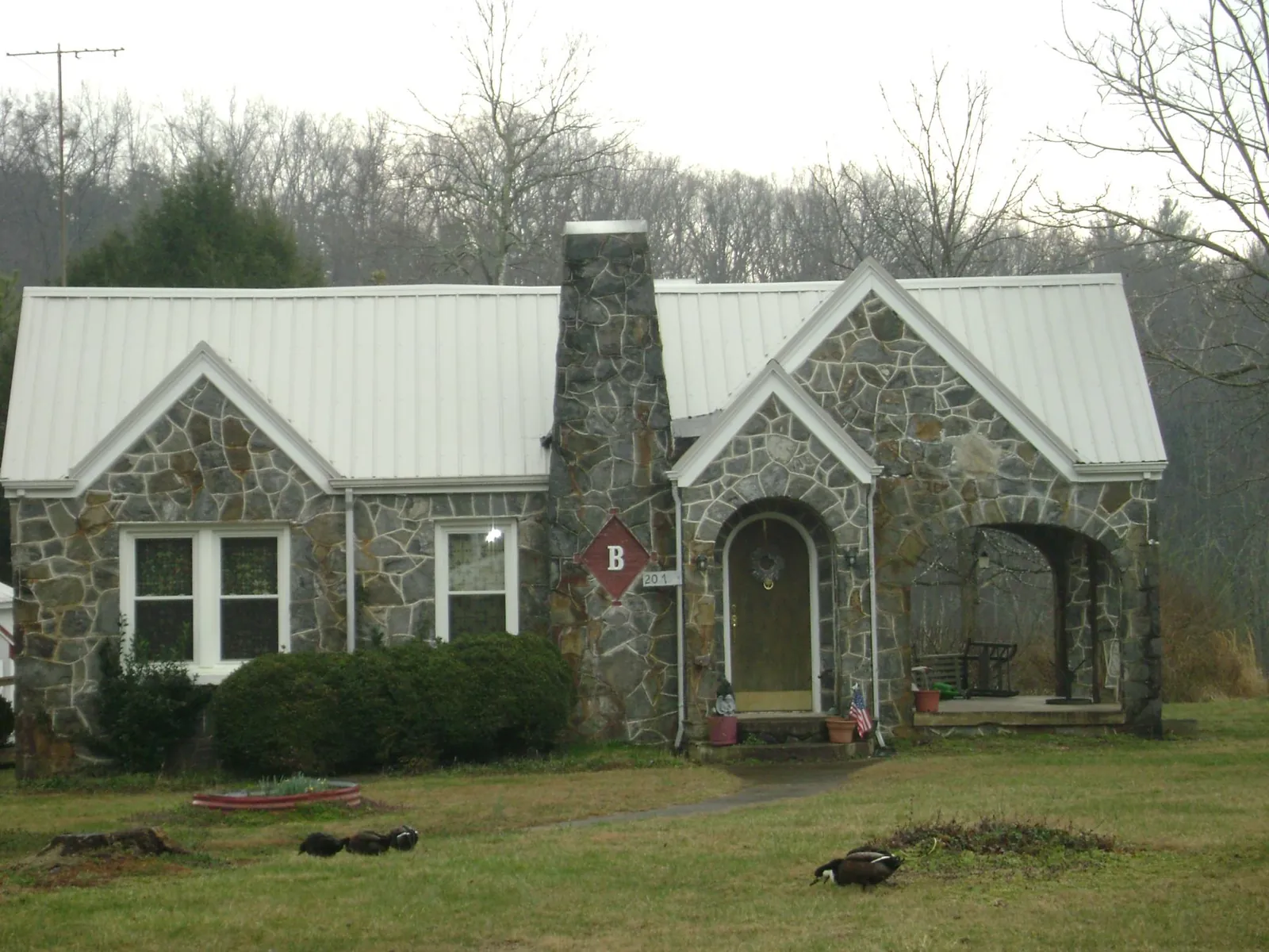 White metal roof on a stone cottage with steep gables in Cresskill