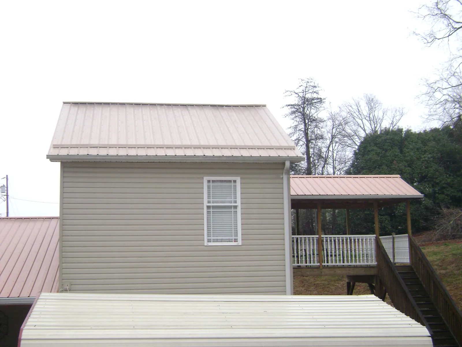 Tan metal roofs on a two story addition and attached porch, from a Roof Replacement job in Cresskill