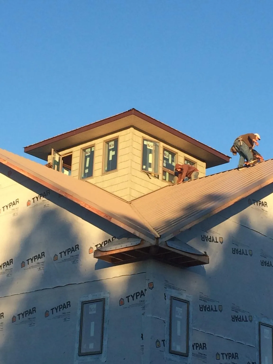 Roofers working around a rooftop cupola on a new metal roof at sunset — Roof Waterproofing in Cresskill by Roofing Brothers
